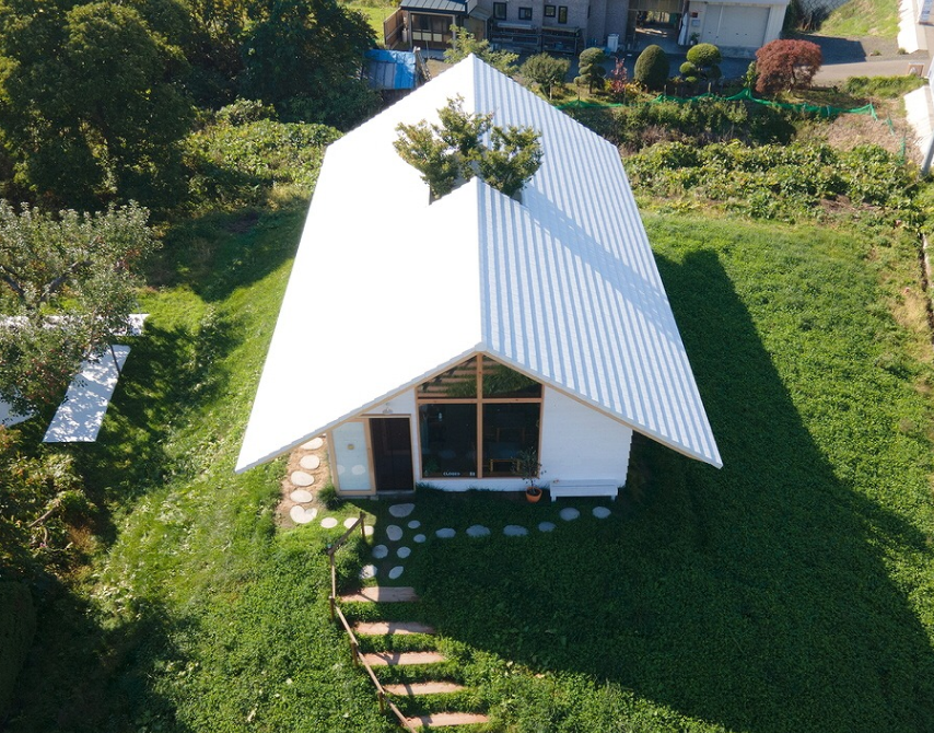 緑の中に佇む白い大屋根の建築外観（スーパートライ110 スマート）