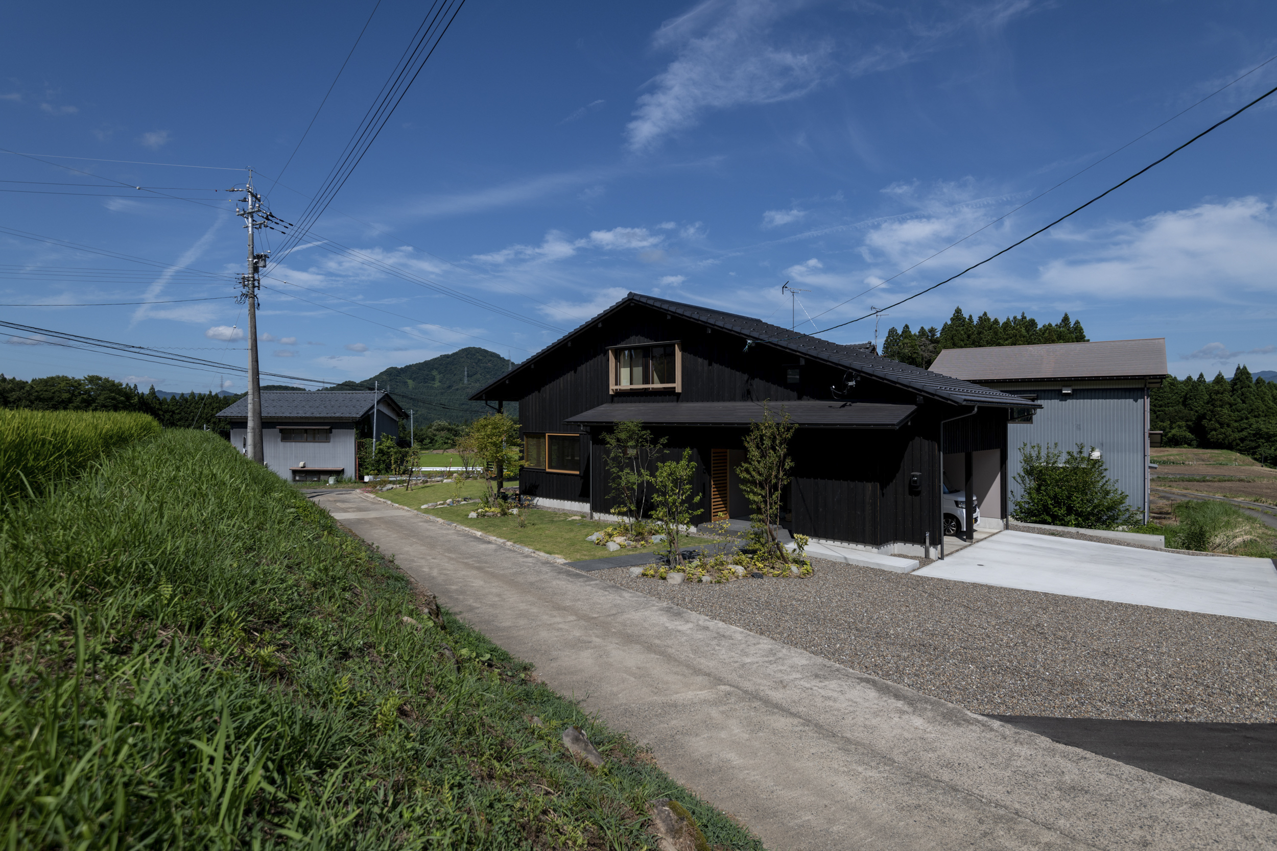 棚田が連なる丘陵地に建つ「平泉寺の家」と、建物に続く道